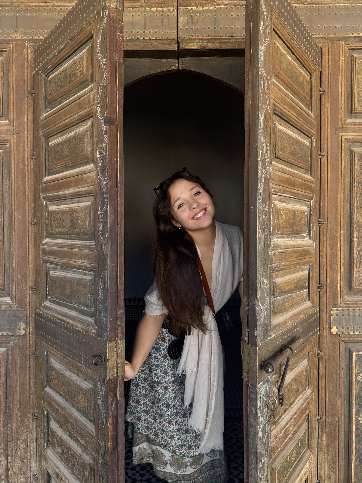 Samantha smiling through an ornate wooden doorway in Morocco